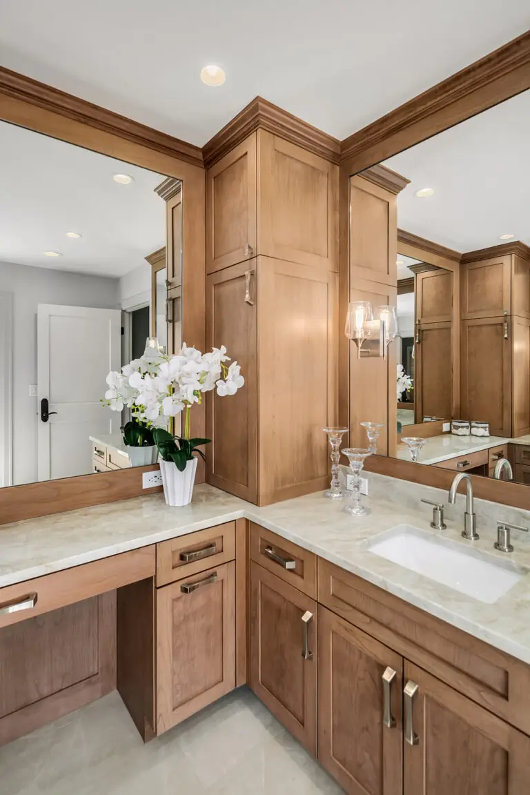Corner vanity with orchids, Taj Mahal quartzite counters and cherry cabinetry with mirrored walls