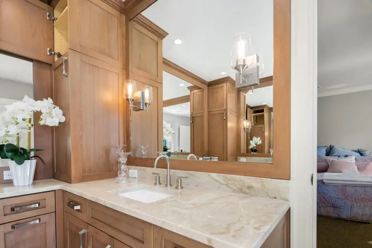 Vanity sink with Taj Mahal quartzite counter and glass sconce, with the bedroom visible through the doorway