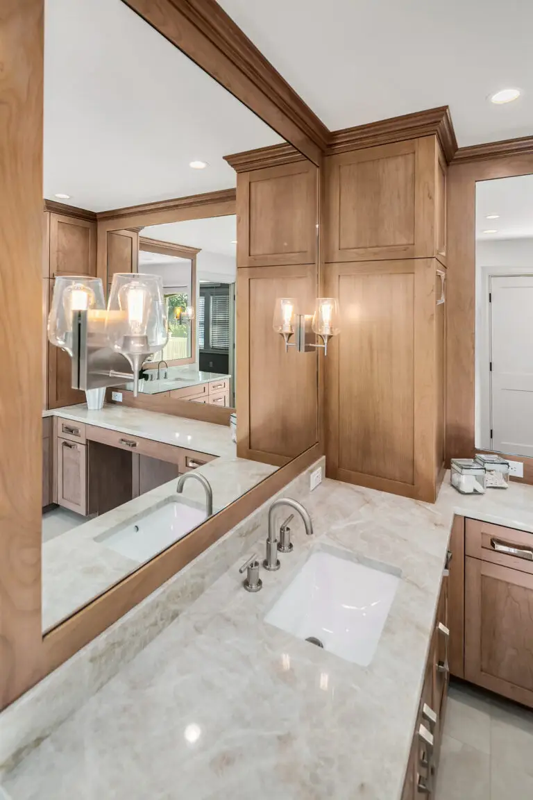 Mirrored vanity wall reflecting double sinks and sconces above a Taj Mahal quartzite counter
