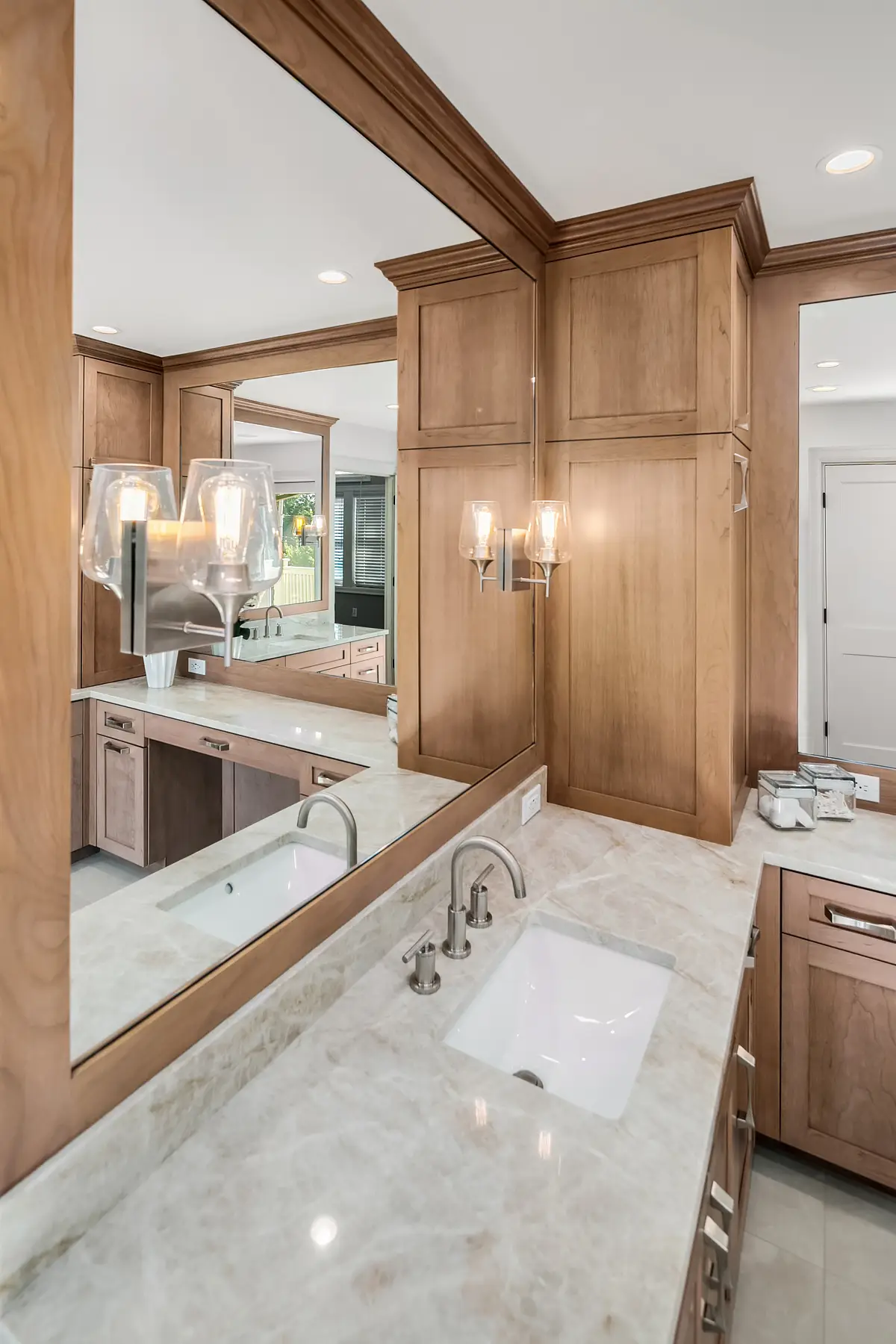 Mirrored vanity wall reflecting double sinks and sconces above a Taj Mahal quartzite counter