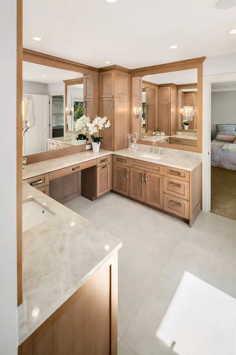 Wide view of cherry vanity with makeup desk, Taj Mahal quartzite counters and bedroom beyond