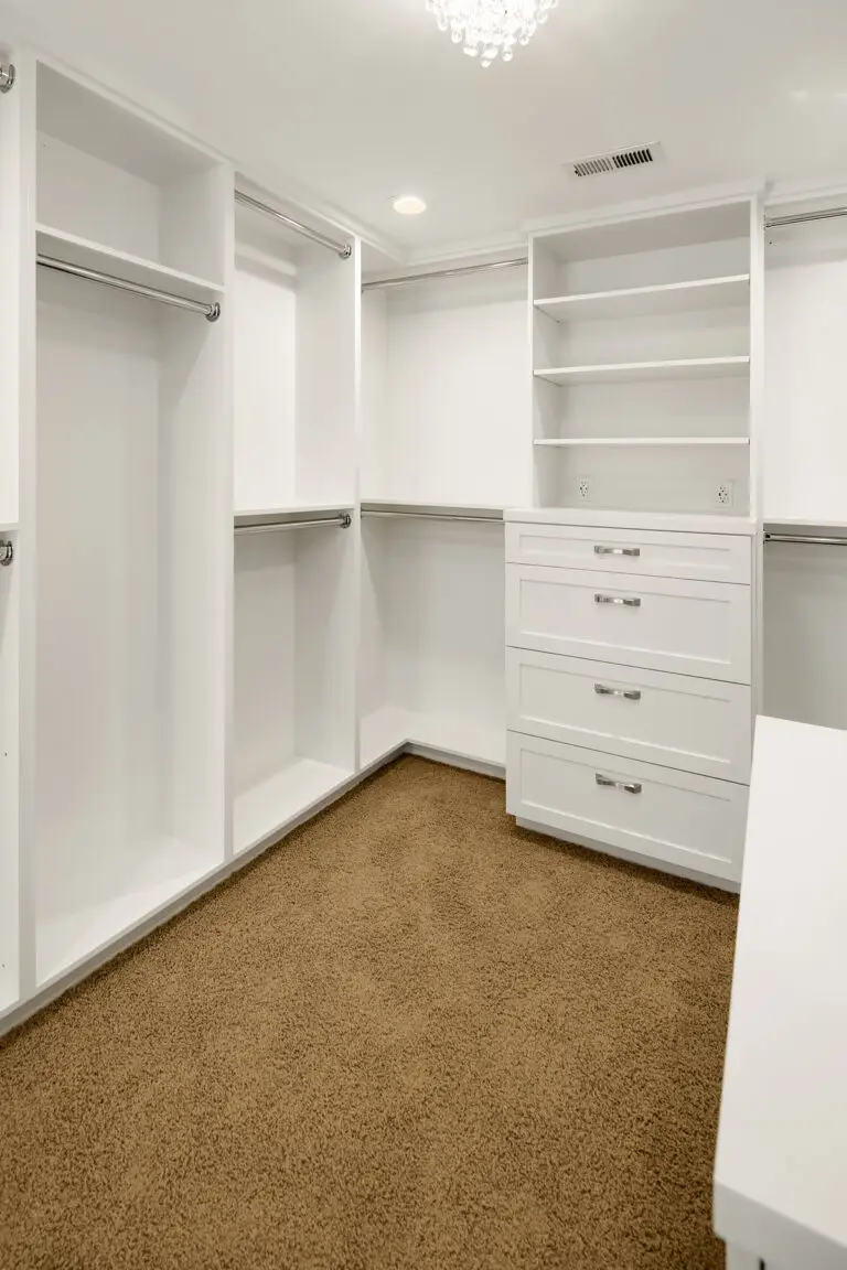 Walk-in closet corner with hanging rods, open shelving and built-in drawer dresser