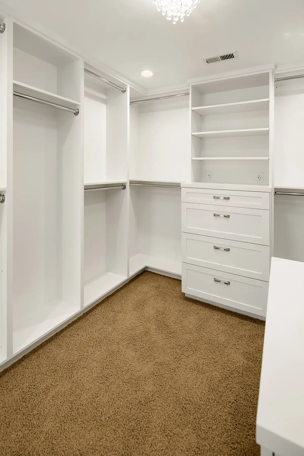Walk-in closet corner with hanging rods, open shelving and built-in drawer dresser