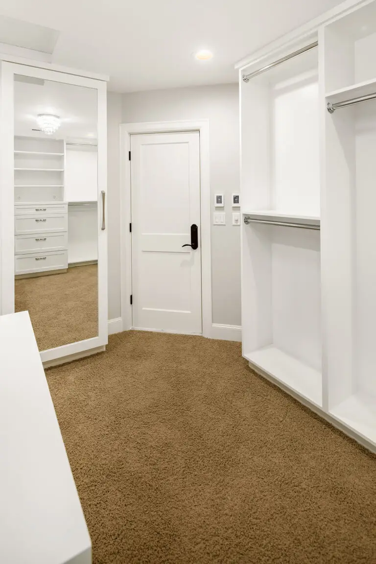 Walk-in closet entry with full-length mirror, white door and open hanging storage