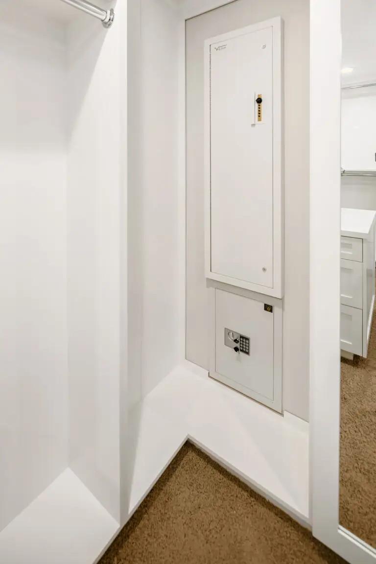 Recessed wall safe and keypad lockbox built into a custom white walk-in closet nook