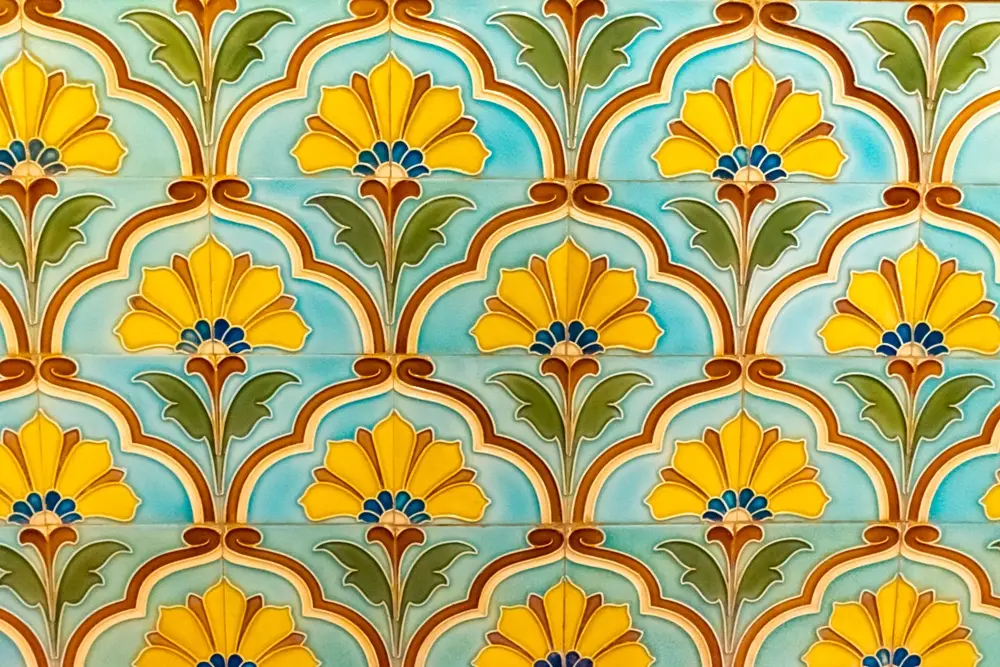 Vintage ceramic wall tiles with yellow flowers and green leaves on a turquoise background
