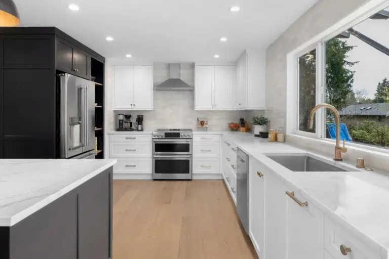 Kitchen with black pantry cabinets, stainless fridge, white quartz counters, brass faucet and wide picture window