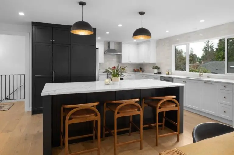Black island with marble-look quartz countertop, arched wood bar stools and black-and-gold dome pendant lights