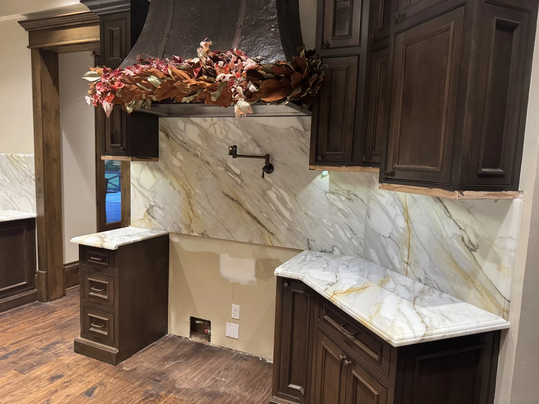 Book-matched Calacatta Gold marble full-height backsplash behind a range with a flush-mounted pot filler
