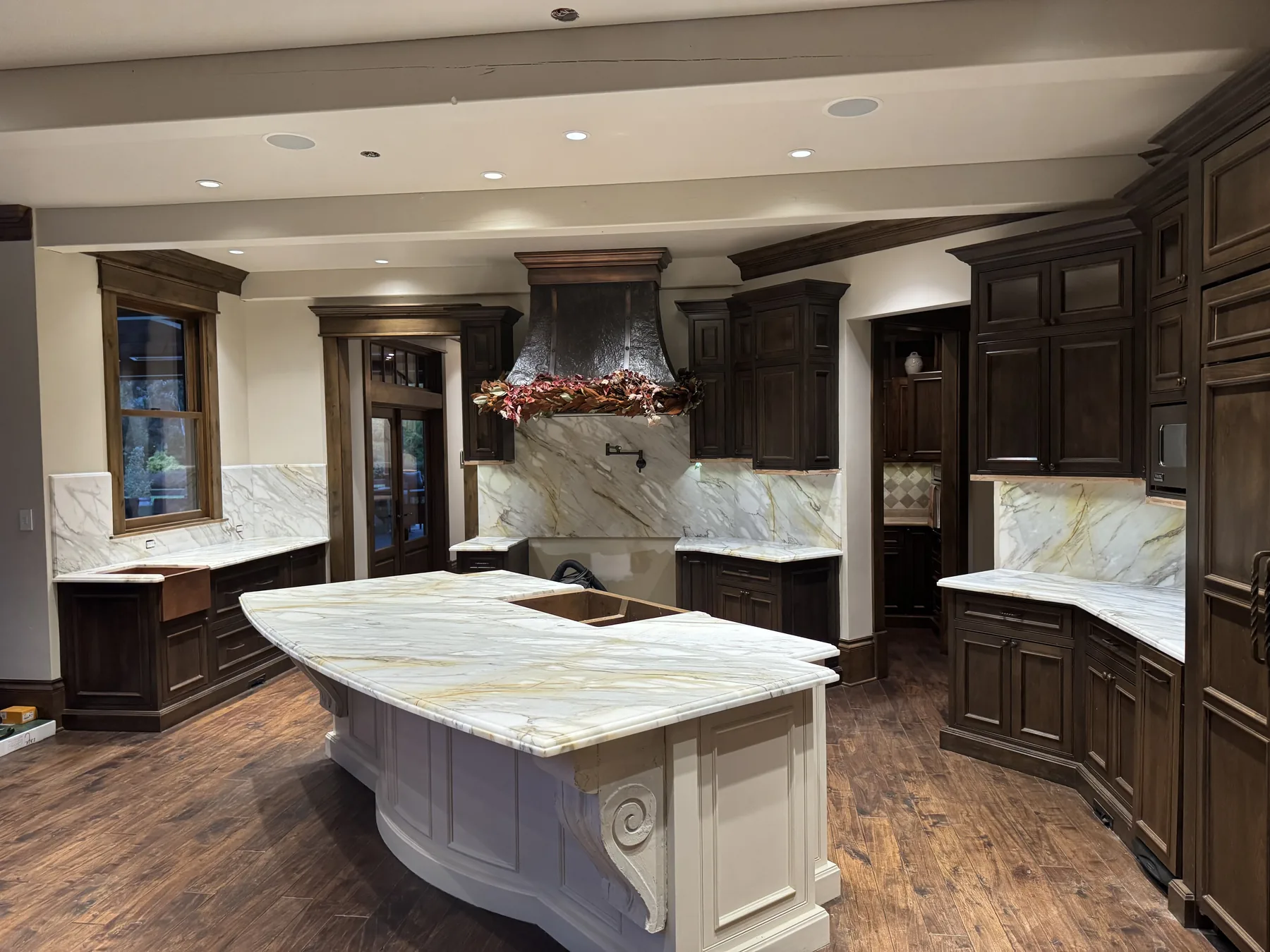 Honed Calacatta Gold marble countertops and full-height backsplash in a Snohomish kitchen with dark walnut cabinetry