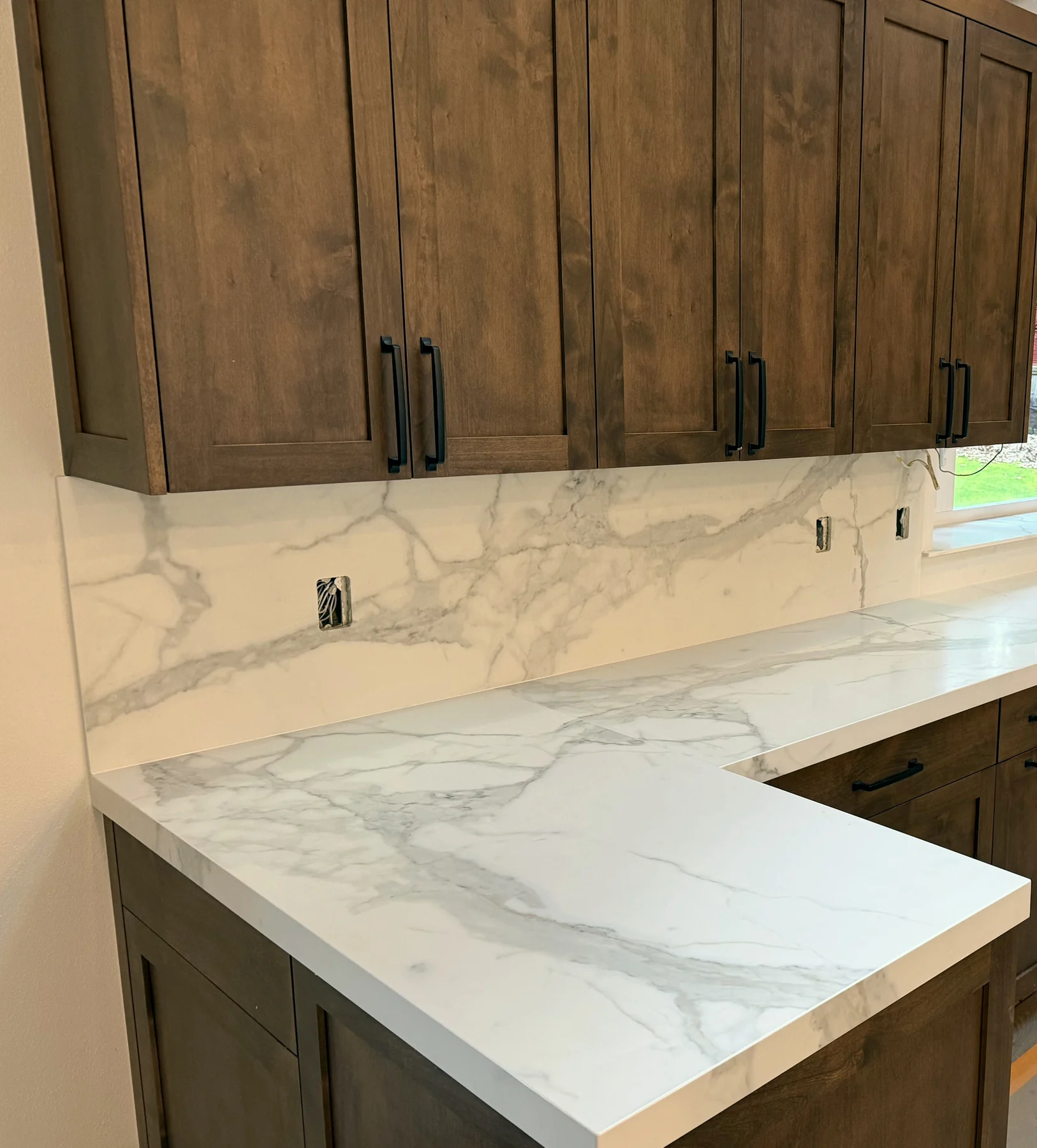 Calacatta Silky porcelain countertops and full-height backsplash with dark stained cabinets in a Woodinville kitchen.