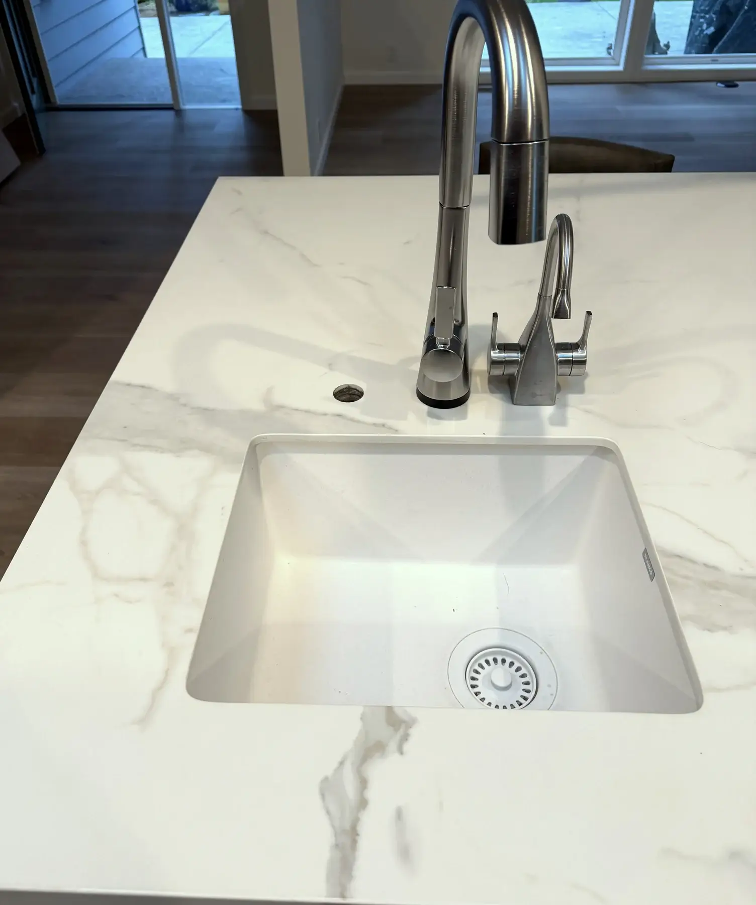 Undermount prep sink set into a Calacatta Silky porcelain kitchen island with soft grey veining.