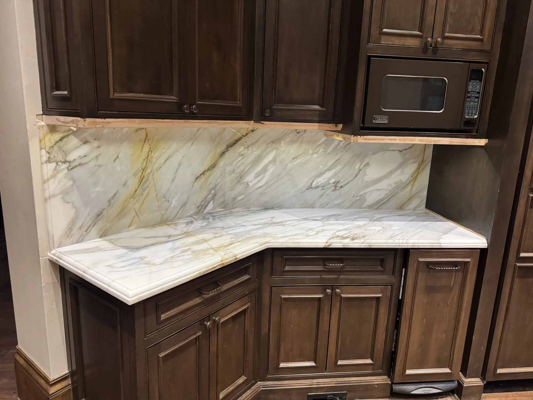 Calacatta Gold marble countertop and full-height backsplash wrapping an inside corner of a kitchen