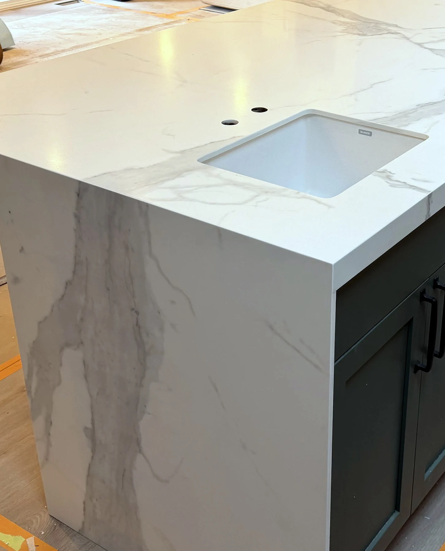 Deep green kitchen island topped with white Calacatta porcelain and a waterfall end panel.