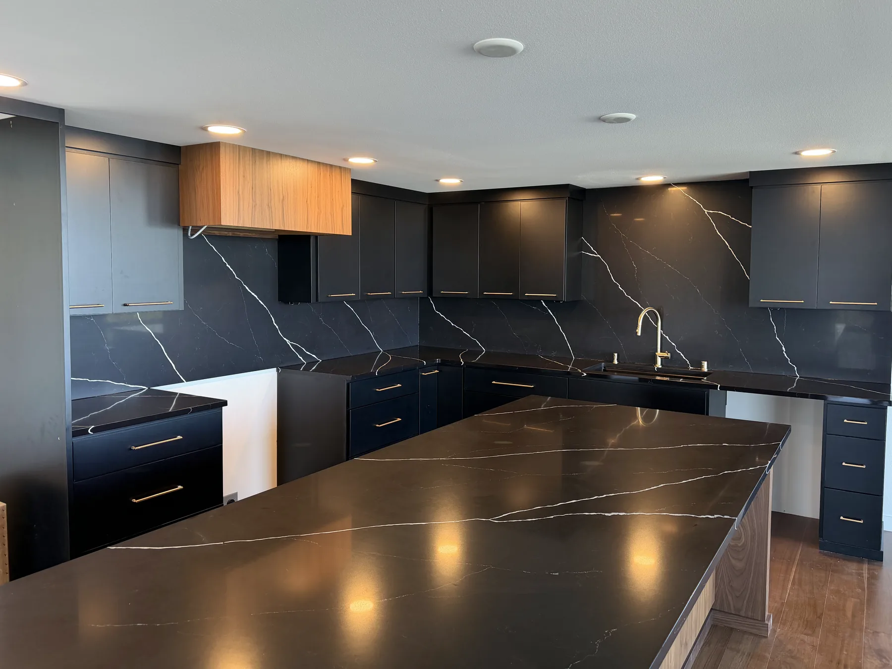 Full-height black quartz backsplash running the length of a kitchen wall with dramatic white veining