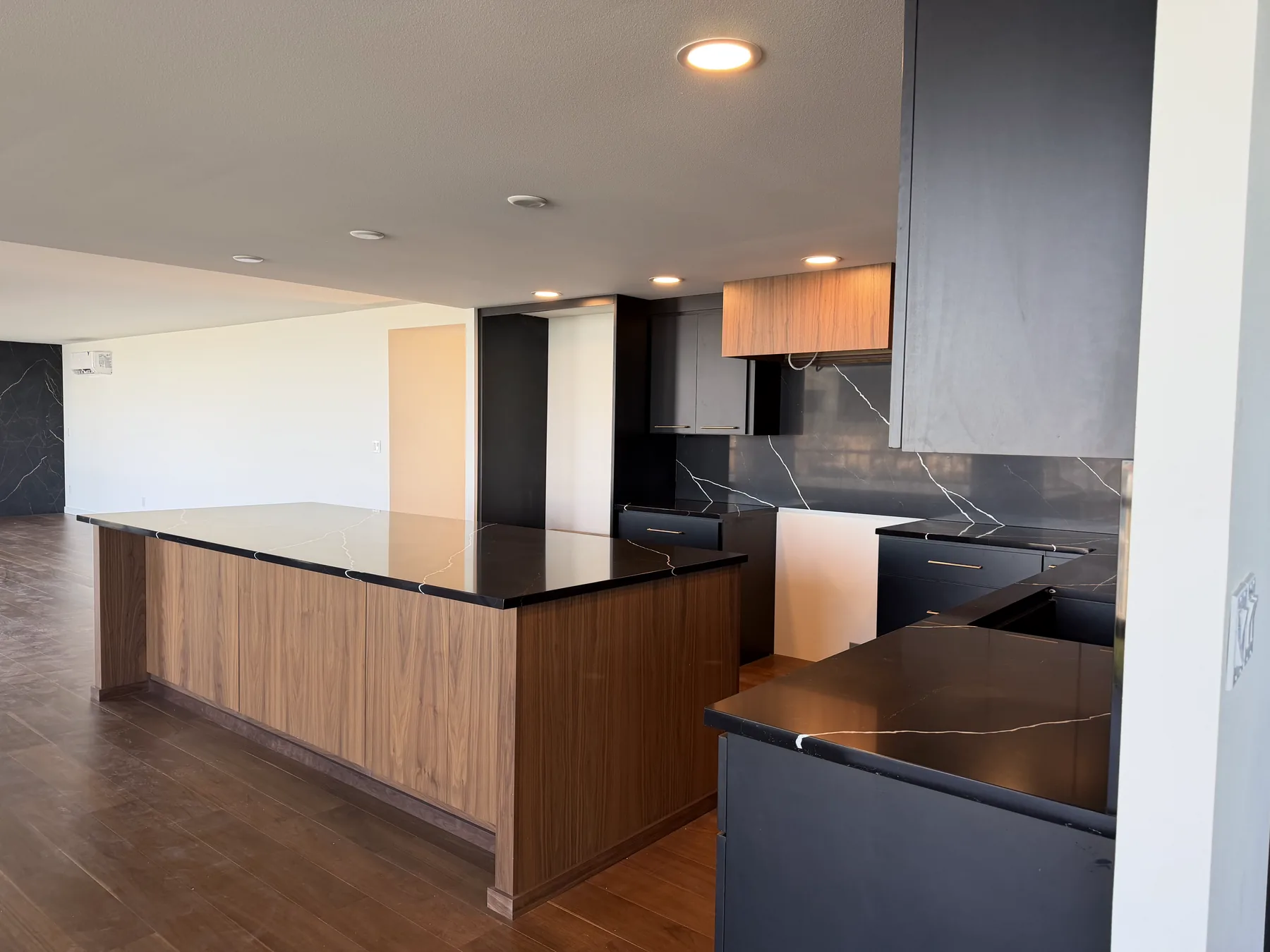 Ten-foot black walnut kitchen island topped with black Marquina Midnight quartz in an open-plan Tacoma condo