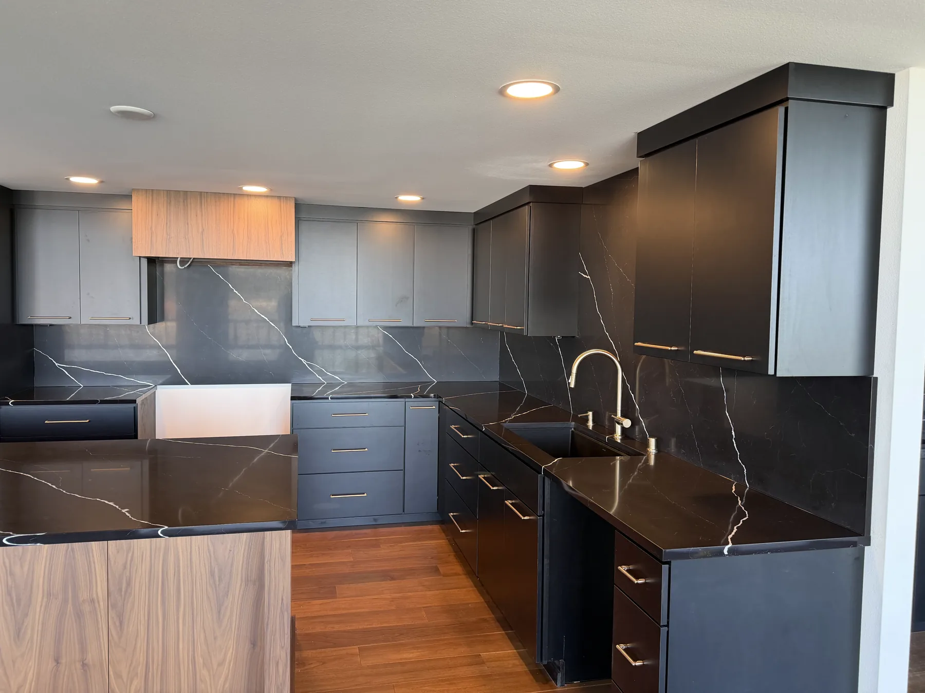 Seamless full-height black quartz backsplash wrapping the corner of a kitchen above matching countertops
